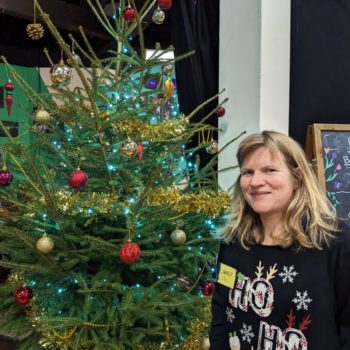 A Caring at Christmas Volunteer next to the Christmas tree