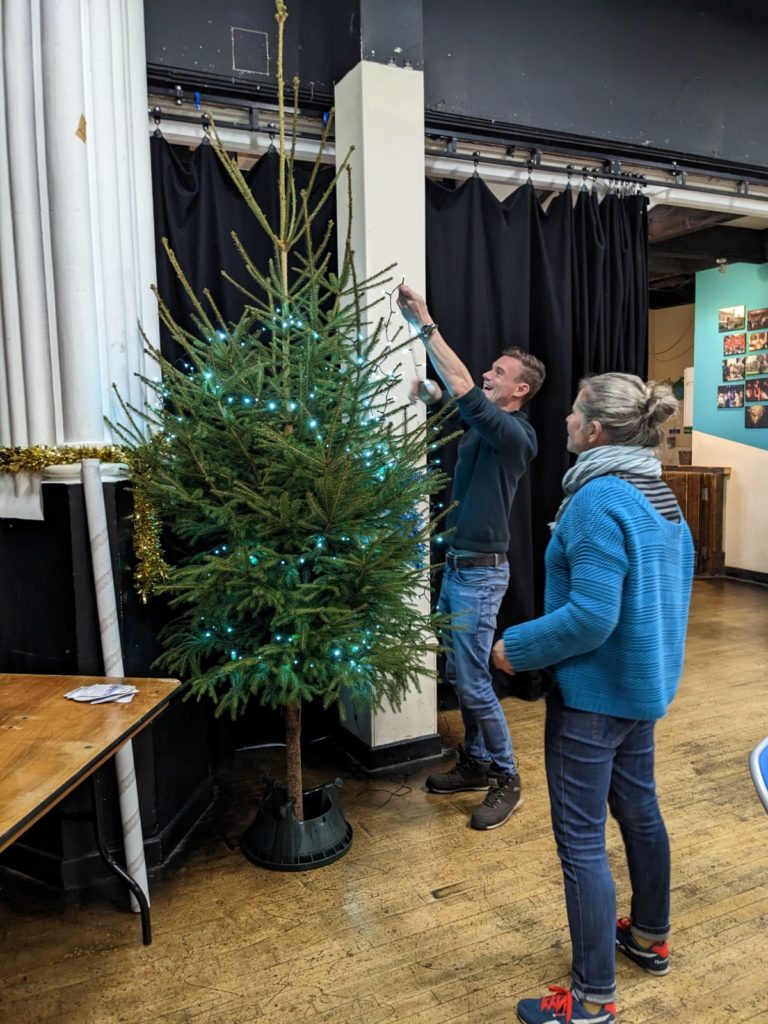 Volunteers adding decorations and lights to the Christmas tree now in situ.