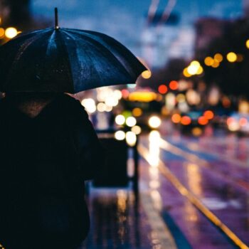 Young person on a street with umbrella in rain
