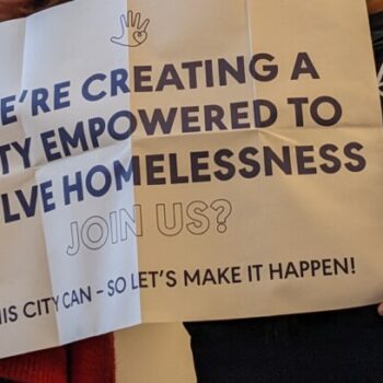 Team members holding a poster of our mission statement to create a city to solve homelessness